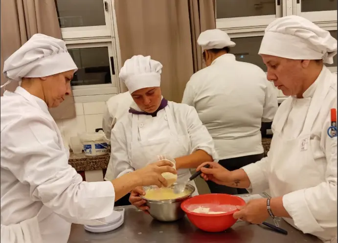 Chef cocinando en una cocina con estufa, ollas e ingredientes, representando la gastronomía.